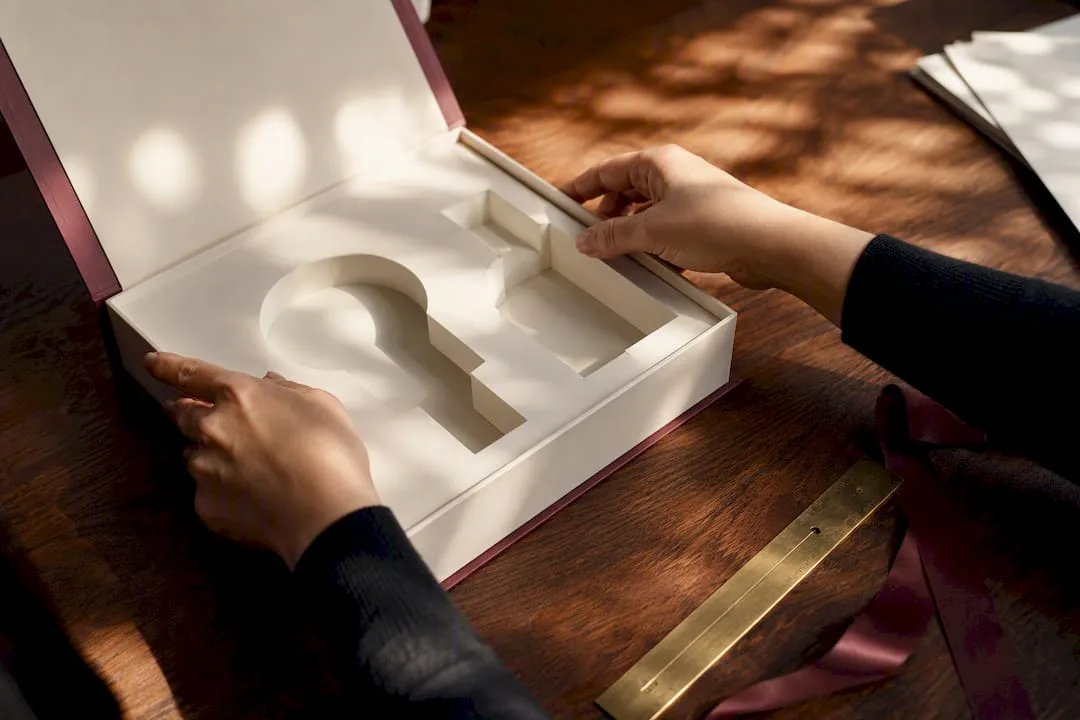 Hands inserting a fitted insert into a luxury cosmetic box