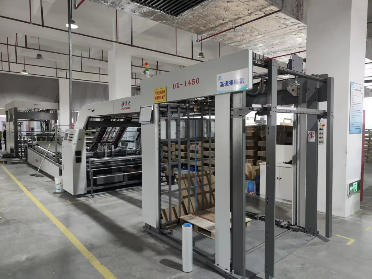A high-speed laminating machine on a packaging factory floor
