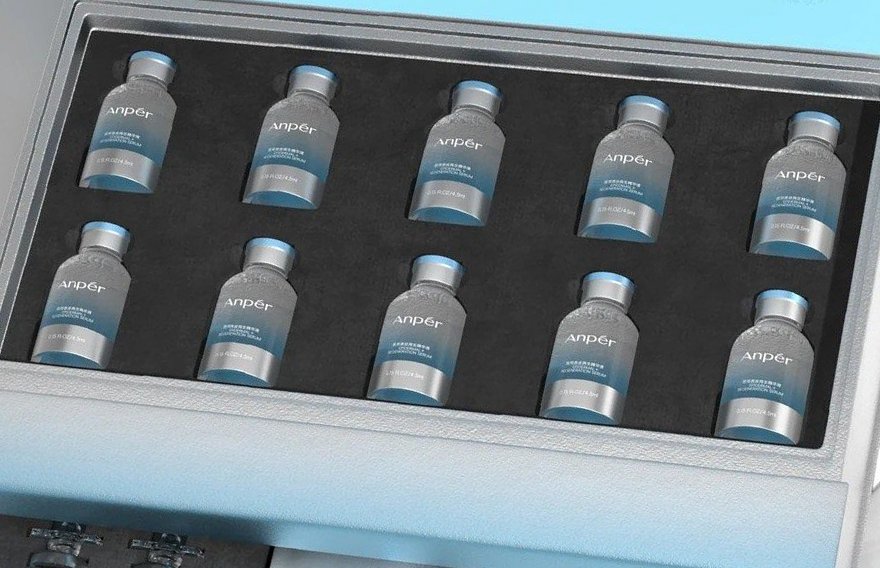 Ten glass serum vials seated in two rows in a die-cut black foam insert, in the upper tray of a pale-blue drawer gift box
