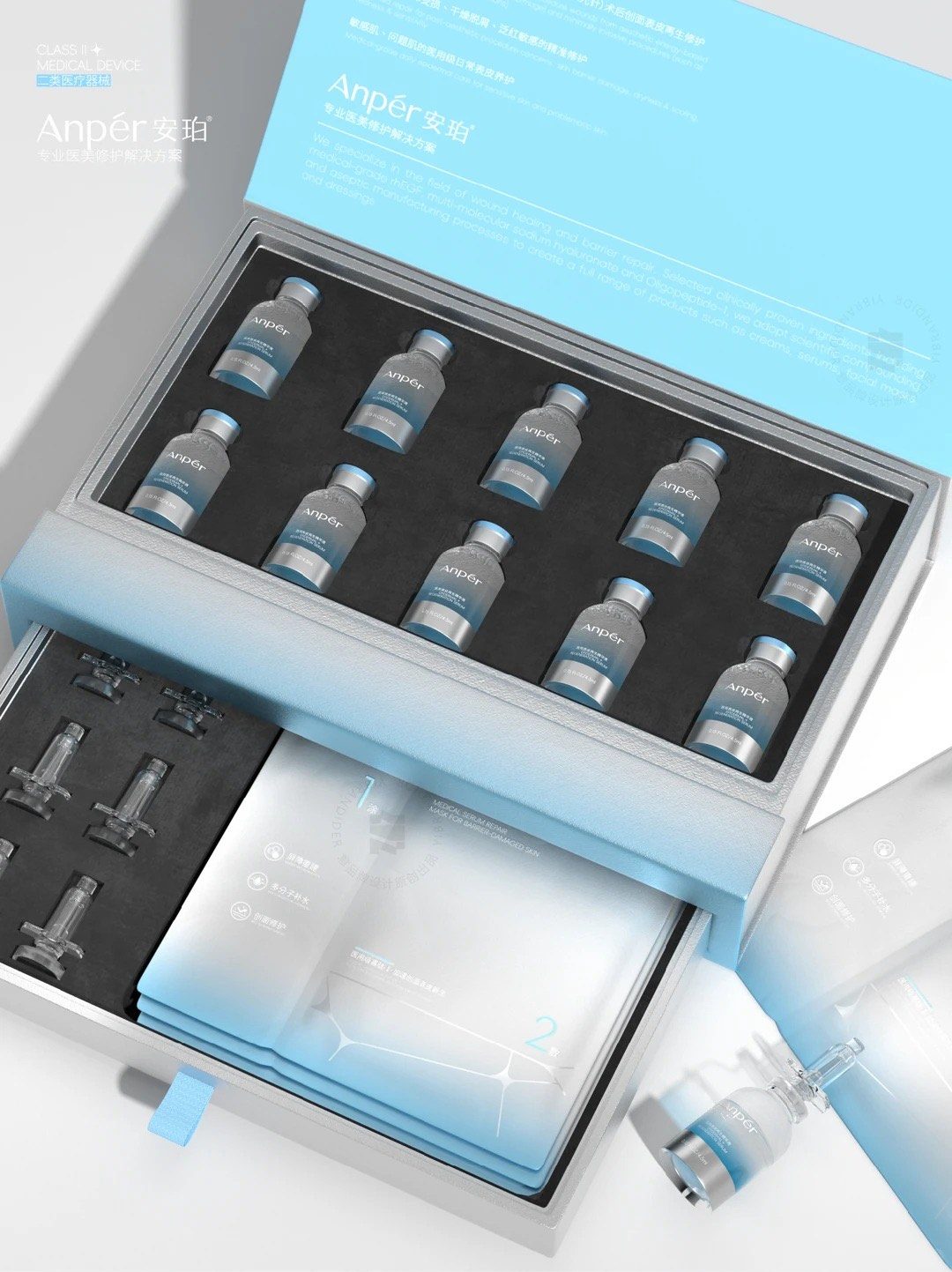 The Anpér drawer box open, with ten glass vials held in a die-cut foam insert and a second tray of masks below