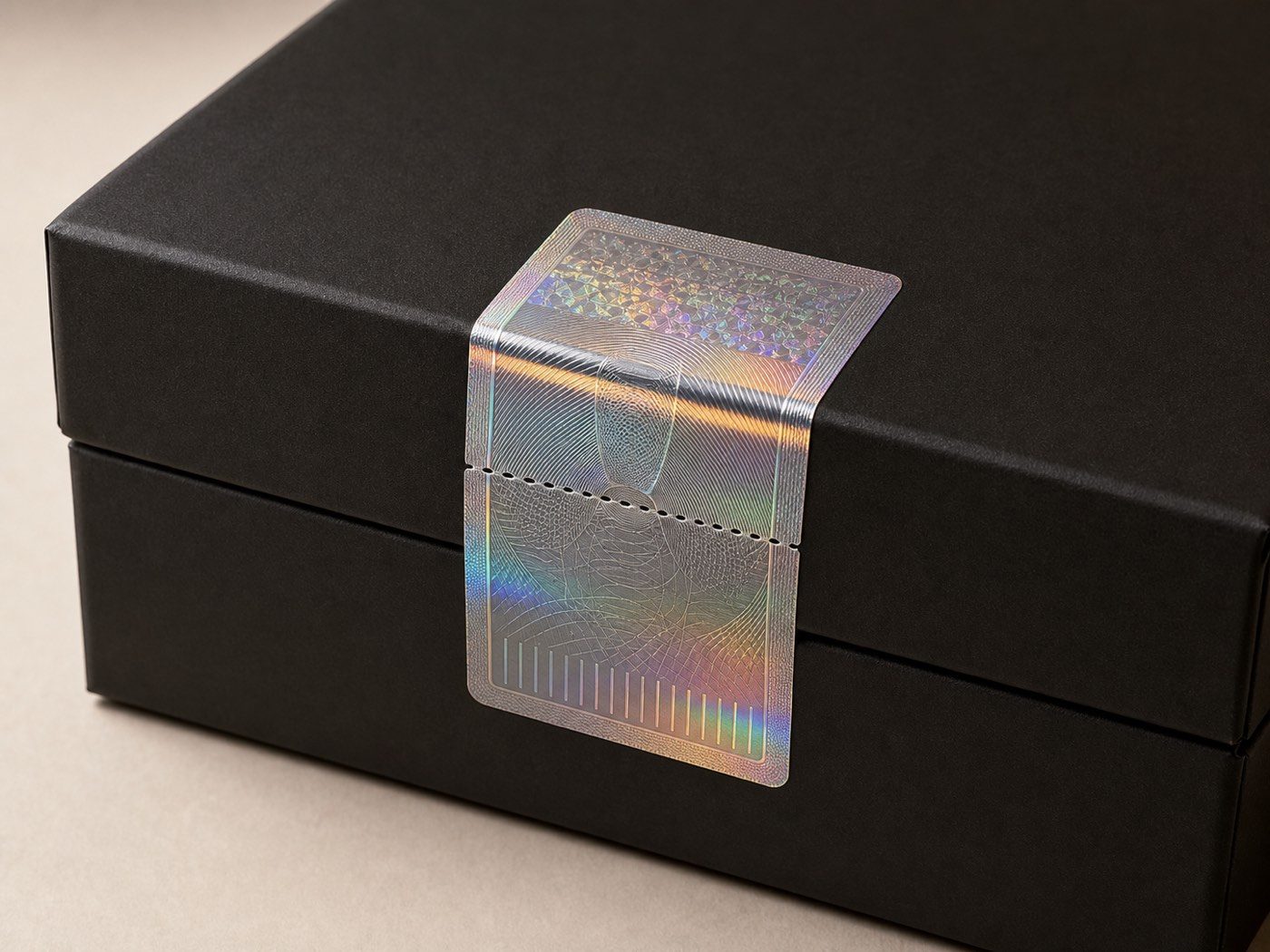 Holographic tamper-evident label bridging the lid seam of an ink-black rigid box