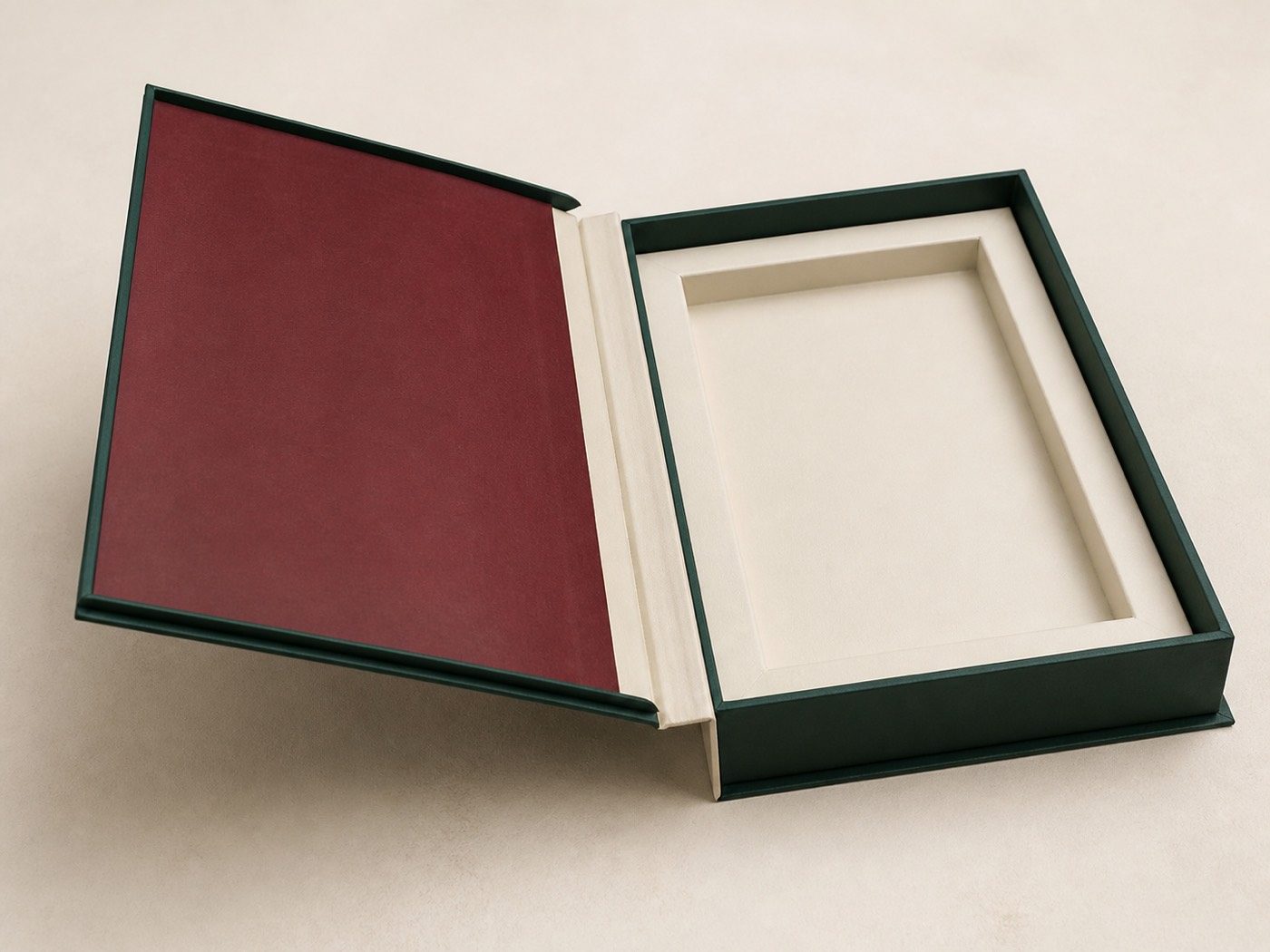 Forest-green book-style rigid box opened to show its full-length spine and fitted ivory insert