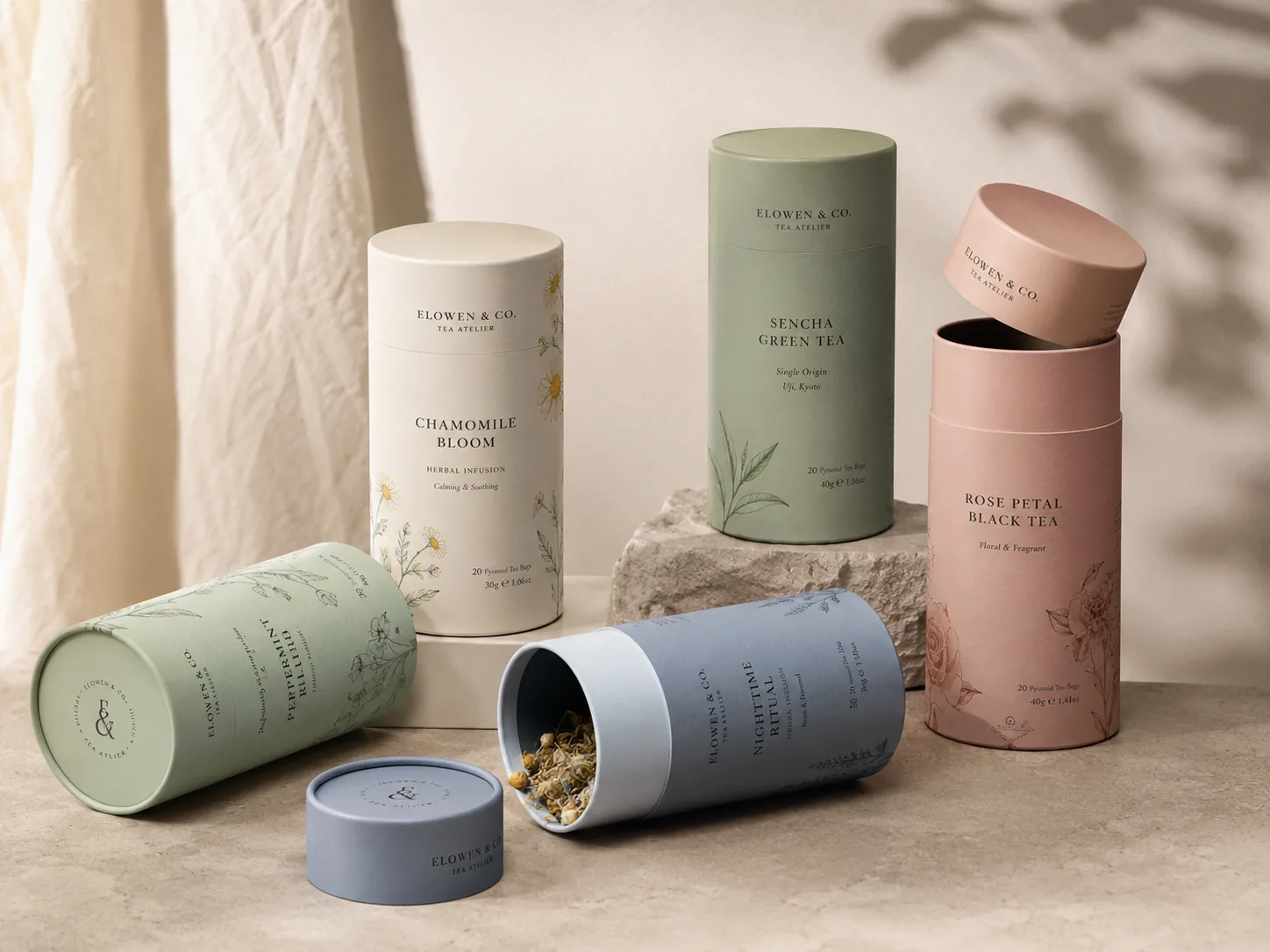 Lid-and-base paper tubes for a tea range in sage, blush and cream, two shown open with their fitted lids removed