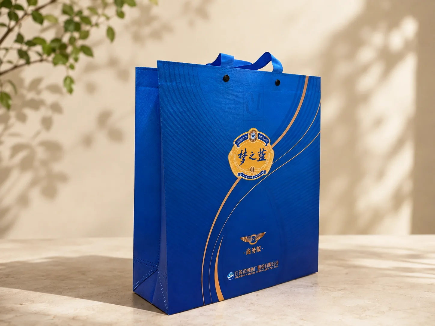 Laminated non-woven carrier bag produced by Yuan Packaging for Yanghe Distillery, printed in blue and gold with reinforced webbing handles, press studs and a gusseted base